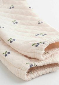 Tessuto trapuntato e leggero di color rosa chiaro con piccole ciliegie ricamate in blu e steli verdi. Presenta un orlo elastico arricciato.