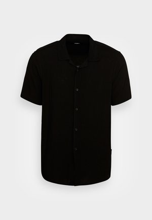 Sort kortærmet skjorte med knapper og krave på en ensfarvet lys baggrund.