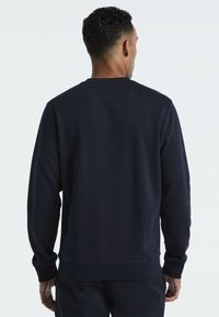 Navyblauwe sweatshirt met een ronde hals, ribbelmanchetten en -zoom. Zachte textuur, minimale stikdetails en een relaxte pasvorm.