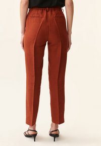 Rustfärgade linbyxor med rak passform och avsmalnande ben. Har en elastisk midja och två bakfickor. Slät textur.