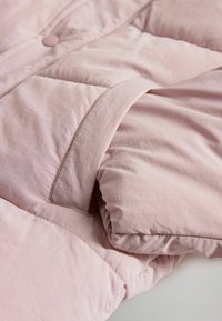 Lyserød pufferjakke med en glat overflade, der har knaplukning og quilted detaljer. Blødt stof med en let glans.