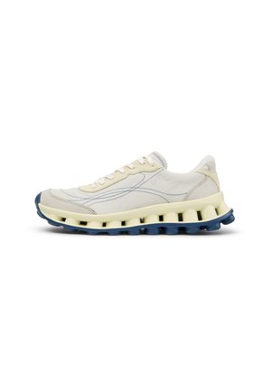 Lyse beige sneaker med blå syning, tyk cremefarvet mellemsål med udskæringer og mørkeblå tekstureret ydersål, set fra siden på hvid baggrund.