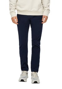 Donkerblauwe corduroy broek met een slim fit ontwerp. Heeft een zachte textuur en zijzakken. G gedragen met een lichtgekleurde hoodie en sneakers.