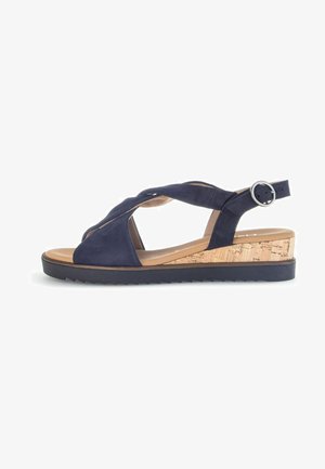Navy blue suede wedge sandal with a cork platform, featuring crisscross straps and an adjustable ankle buckle. Textured outsole for grip.