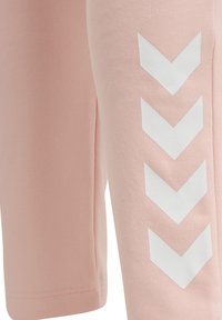 Ljust rosa tyg med fyra vita nedåtriktade chevronformer som är vertikalt placerade på högra sidan.