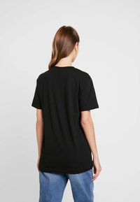 Svart bomullströja med korta ärmar, rund halsringning och avslappnad passform. Enfärgad design, inga synliga mönster eller detaljer.