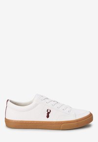 Zapatilla de lona blanca con suela de goma, con un logo burdeos en el lateral y seis ojales para los cordones. Textura suave y diseño sencillo.