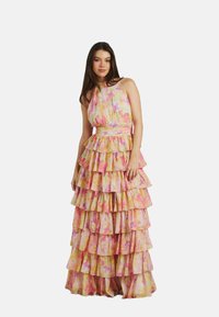 Lungo abito a strati realizzato in tessuto leggero. Presenta un motivo floreale colorato in rosa e giallo, con collo halter e una cintura in vita.