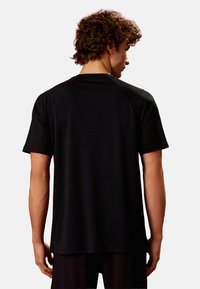 Sort atletisk T-shirt med korte ærmer, glat tekstur og rund halsudskæring. Har raglan skuldre for let bevægelse.