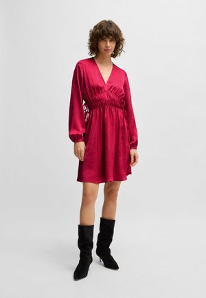 Fuchsia dress with long sleeves, deep V-neck, gathered waist, and drawstring detail. Model paired it with black, knee-high suede boots.