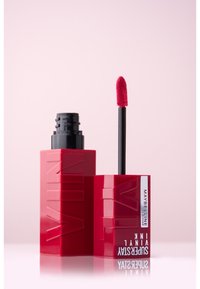 Maybelline Superstay Liquid Lipstick i en djärv röd rektangulär tub, med en svart applicerare med en fluffig spets.
