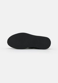 Black shoe sole with a smooth, rounded front and vertical ribbed texture. Lightweight material, designed for traction and durability.