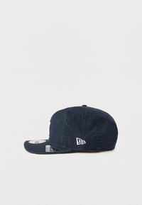 Gorra de béisbol azul marino fabricada en tela, con visera curva, logotipo bordado en el lado izquierdo y cinta ajustable en la parte posterior.