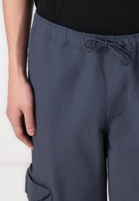 Cargo shorts in dark navy fabric with an elastic waistband and drawstring. Features side pockets and a smooth texture.