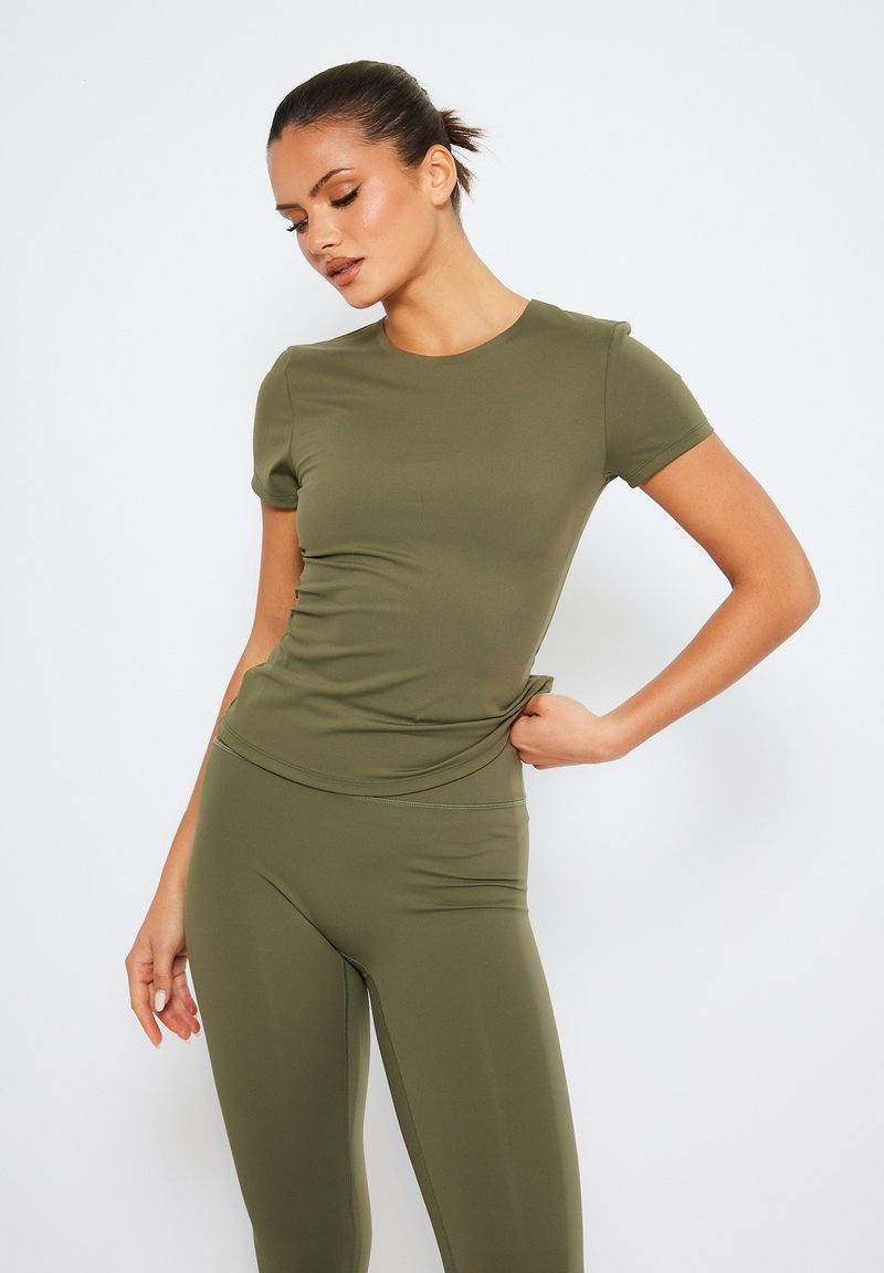 Olivgrön träningsöverdel med korta ärmar, åtsittande design, slät textur och rundad halsringning, matchad med leggings i samma färg.