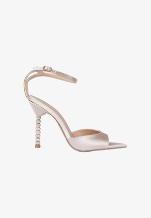 Scarpa con tacco alto in raso a punta aperta con cinturino alla caviglia ornato con strass e tacco decorativo con perline in colore beige chiaro.