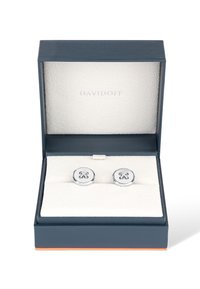 Silver cufflinks displayed in a navy blue box with a white textured lining; features a floral-like design embossed on the front.