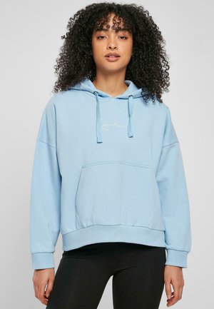 Lyseblå hoodie i blødt materiale med en kængurulomme, snor i huen og en diskret hvid logoaccent på brystet. Ribbet kant og manchetter.