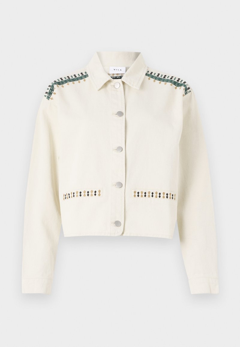 Veste courte en crème en denim, avec des finitions vertes et des coutures décoratives en doré et noir le long des poches et des épaules.