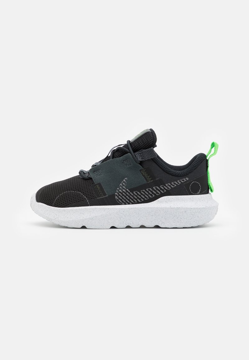 Black athletic shoe with mesh upper, grey accents, and a white speckled sole. Features green pull tab and textured patterns on the side.