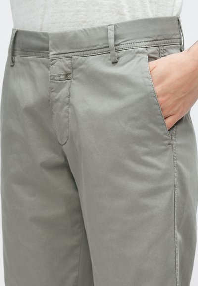 Pantalon gris clair à texture douce avec une finition lisse, doté de poches latérales et d'une ceinture standard sans éléments visibles.