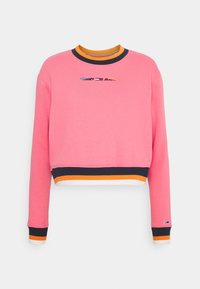 Jasně růžová krátká mikina s dlouhými rukávy, námořnicky modré a oranžové pruhované manžety a lem, a malým logem "Tommy Jeans" s vlajkou na prsou.