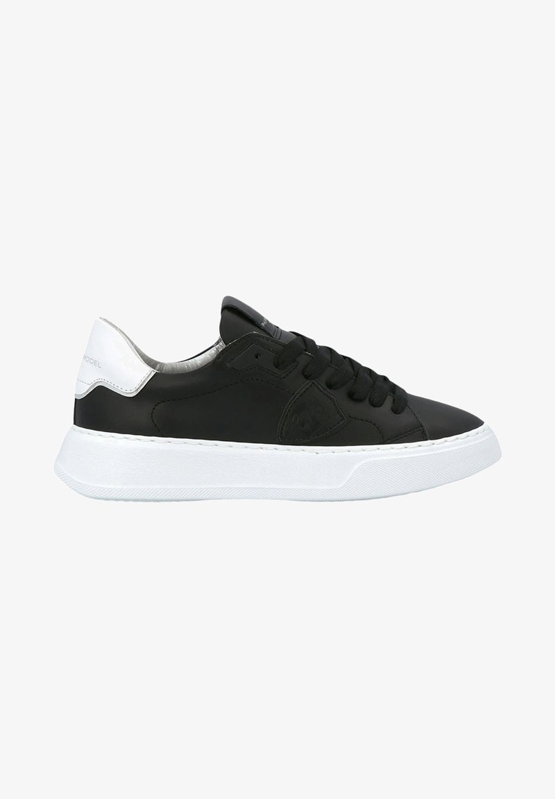 Baskets en cuir noir avec semelle en caoutchouc blanc, dotées de lacets noirs, d'une languette rembourrée et d'un accent talon blanc brillant.