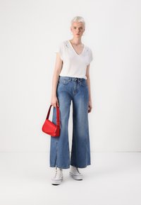 Valkoinen t-paita pitsireunalla, korkeavyötäröiset leveät siniset farkut, punainen nahkakäsilaukku ja valkoiset korkeat tennarit. Yksinkertainen, rento asu.