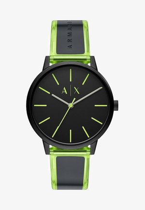 Montre analogique noire avec un visage rond, des marqueurs d'heure verts et des aiguilles. Le bracelet est vert translucide avec un accent noir.