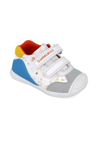 Sneaker bianco per bambini con accenti grigi, tallone blu e collo giallo brillante. Presenta doppie cinghie in Velcro e motivi a stelle colorate.