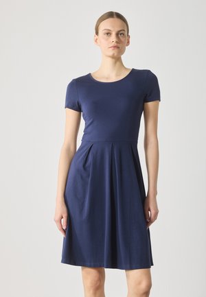 Navy blue cotton dress with short sleeves, round neckline, fitted bodice, and a flared skirt featuring pleats for added movement.