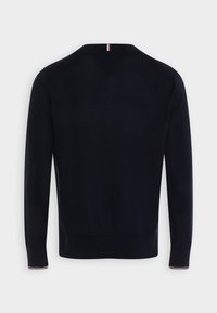 Maglione blu navy realizzato in morbido tessuto a maglia, con maniche lunghe, scollo a V e dettagli a contrasto in rosso e bianco sul colletto.