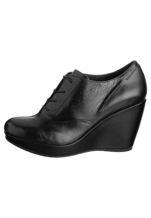 Black leather wedge shoes with a smooth texture, rounded toe, lace-up design, and a high wedge heel, featuring subtle stitching details.
