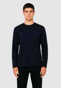 Camicia a maniche lunghe blu marino in cotone con scollatura a girocollo e silhouette aderente, mostrata su uno sfondo neutro.