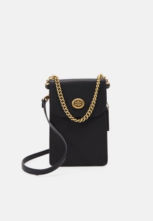 Zwarte gestructureerde leren crossbody tas met gouden kettingdetail en draai-sluiting op de voorflap tegen een witte achtergrond.