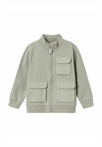 Chaqueta de cremallera verde claro con cuello alto, que cuenta con dos bolsillos en el pecho y puños acanalados. Fabricada con un tejido suave y texturizado.