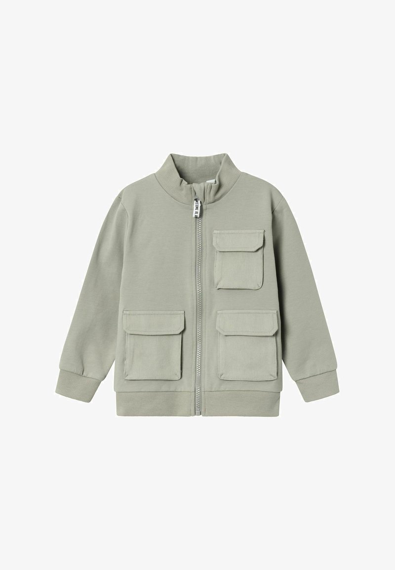 Chaqueta de cremallera verde claro con cuello alto, que cuenta con dos bolsillos en el pecho y puños acanalados. Fabricada con un tejido suave y texturizado.