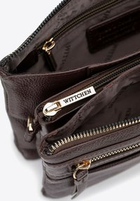 Ciemnobrązowa torebka skórzana z wieloma zamykanymi na zamek przegrodami, złotym okuciem oraz teksturowanym wykończeniem. Wyłożona brązową tkaniną.