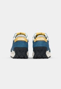 Blue and gray suede sneakers with yellow accents, textured outsole, and logo on the heel. Padding around the collar for comfort.