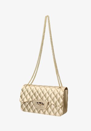 Beige doorgestikte handtas met goudkleurige kettingriem en rechthoekige draaisluiting, getoond hangend tegen een witte achtergrond.