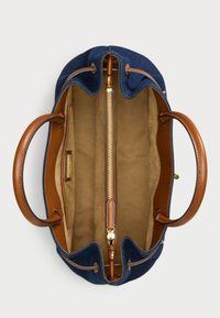 Niebieska torba dżinsowa z brązowymi skórzanymi uchwytami i akcentami. Posiada zamykaną na zamek kieszeń wewnątrz z miękką, jasną podszewką.