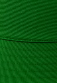 Tessuto verde con un pattern diagonale testurizzato. Presenta cuciture a punto e una superficie liscia. Il design è uniforme e di un colore solido.