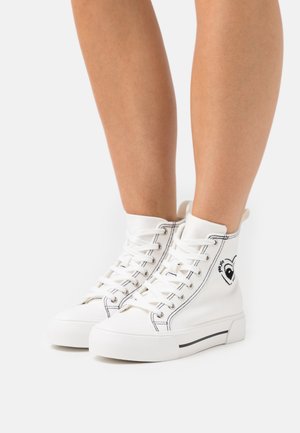 Sneakers bianche alte in tela con cuciture nere, caratterizzate da un design grafico a forma di cuore e suole in gomma bianche.