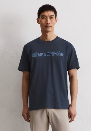 T-shirt en coton bleu marine avec un grand graphique bleu "Marc O'Polo" sur le devant, manches courtes et col rond. Coupe décontractée.