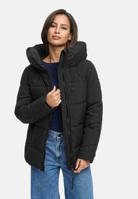 Black puffer jacket with a hood, featuring a quilted design, front zipper closure, and drawstring accents. Worn over a dark top.