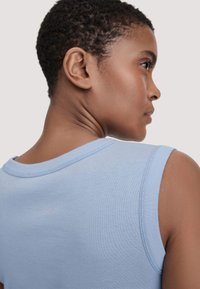 Hellblaues ärmelloses Oberteil mit Rundhalsausschnitt, gerippter Textur und sichtbaren Nähdetails an den Schultern und am Halsausschnitt.