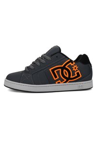 Dunkelgrauer Sneaker mit schwarzen Akzenten, grauen Schnürsenkeln und einem orangefarbenen Logo. Glattes synthetisches Material mit einem strukturierten Fersenbereich, Gummisohle.