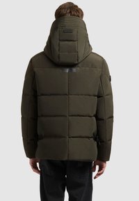 Alyvuogių žalios spalvos pūkinė striukė su aukštu apykakle, horizontaliais dygsniuotais skydais ir reguliuojamomis šoninėmis dirželėmis. Lygi tekstūra su kapišonu.