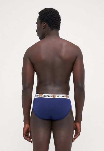 Navy blue men's briefs with a contrasting white waistband featuring a bear logo and "MOSCHINO" text. Soft, smooth fabric with a fitted shape.