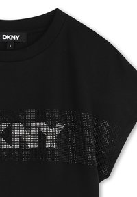 Camiseta negra de manga corta hecha de algodón, con un gran logo de DKNY en un patrón texturizado de puntos en la parte frontal.